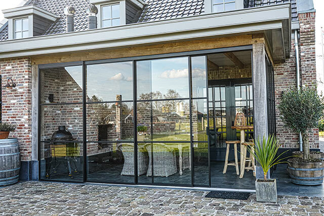 Metalen schuifdeuren van Aluwdoors geplaatst in een veranda in Nunspeet