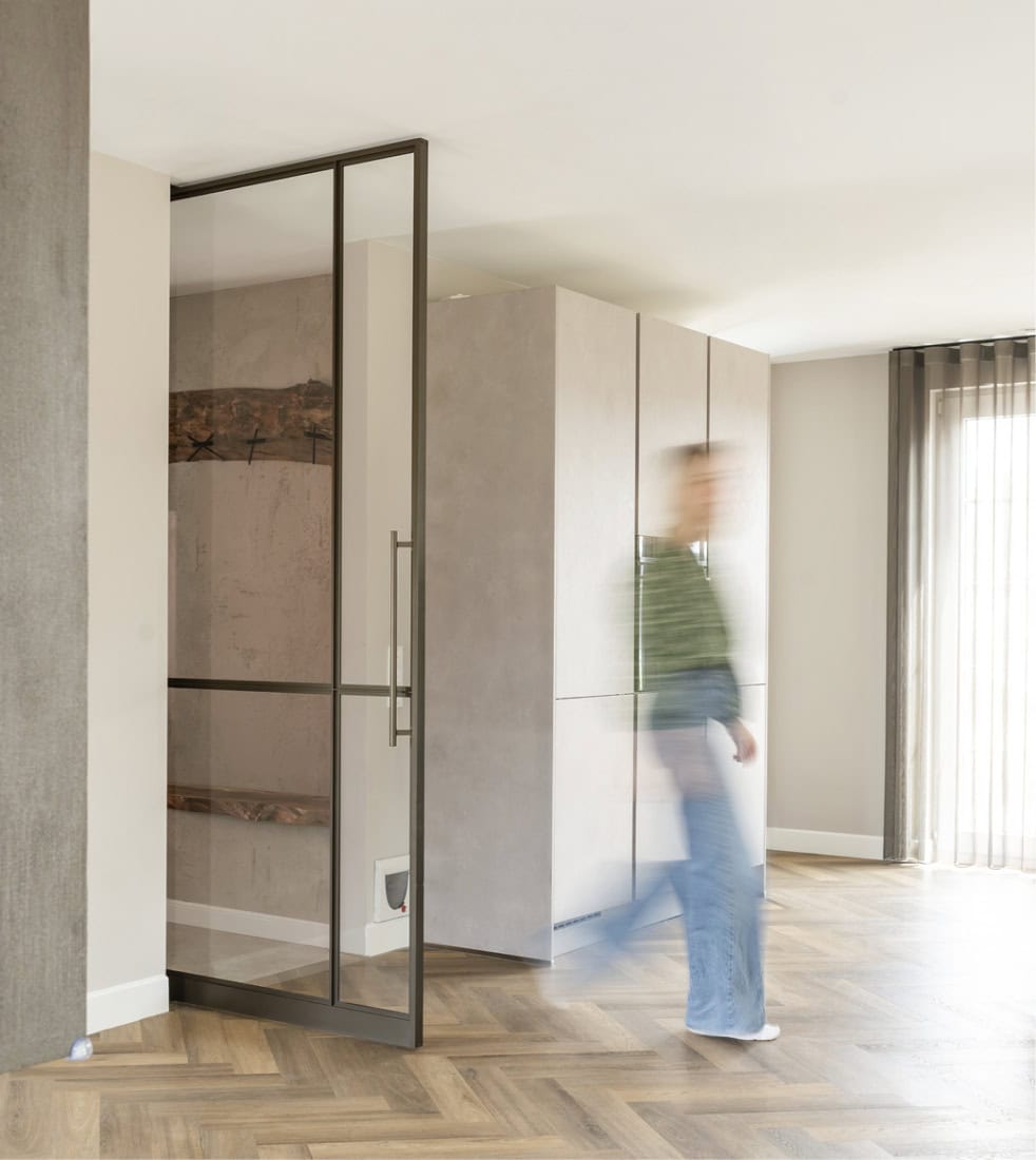 Deur van staal en glasschermen in modern interieur met houten vloer.