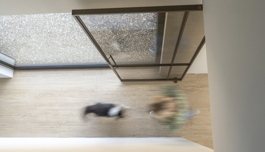 Lichtgewicht stalen schuifdeur met glas in zwart frame, moderne binnen- en buitenruimte, naadloze afwerking en strakke lijnen, op maat gemaakt door Aluwdoors.