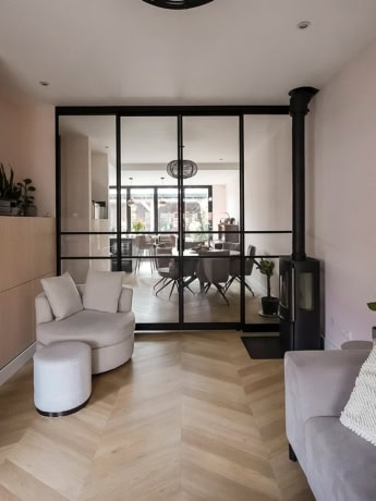 Elegante stalen scheidingswand met zwart metalen frame tussen de woonkamer en eetkamer, maatwerk en stijlvol design.