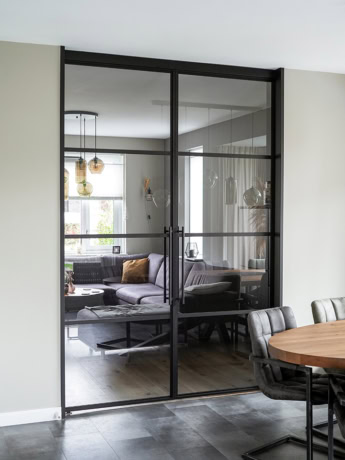 Elegante stalen scheidingswand met glazen panelen voor een moderne woonruimte, op maat gemaakt door Aluwdoors.
