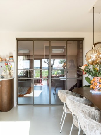 Glazen schuifdeur met stalen frame voor een moderne interieurafwerking.