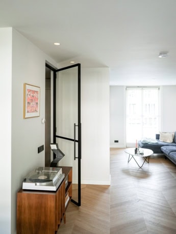 Steel dividing door with black frame and handle in a modern living room, custom-made by Aluwdoors, for a sleek and durable interior finish.