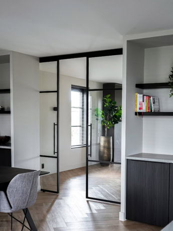 Zwarte stalen schuifdeuren en scheidingswanden van aluminum in een modern interieur.