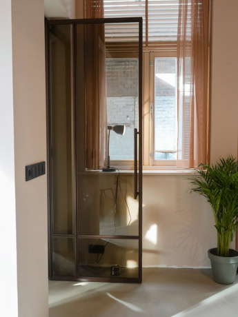 Stalen deur met glas en zwart frame voor scheiding van kamers of kasten, elegante en industriële uitstraling, op maat gemaakt voor modern interieur.