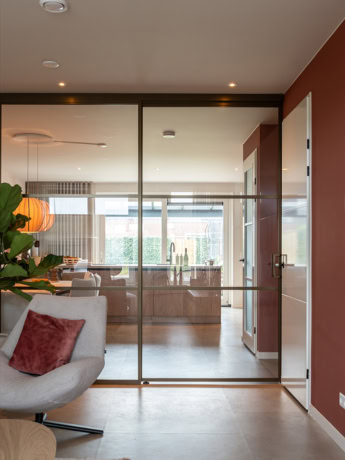 Strakke stalen schuifdeur met glazen panelen voor moderne scheidingswanden en binnendeuren, op maat gemaakt door Aluwdoors voor stijlvolle indelingsopties.