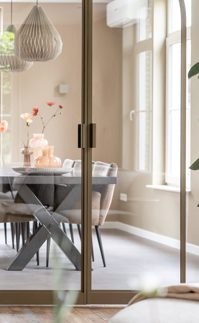 Strakke glazen scheidingswand met stalen frame en handvatten, geschikt voor woning- en kantoorinterieur, modern en functioneel design.