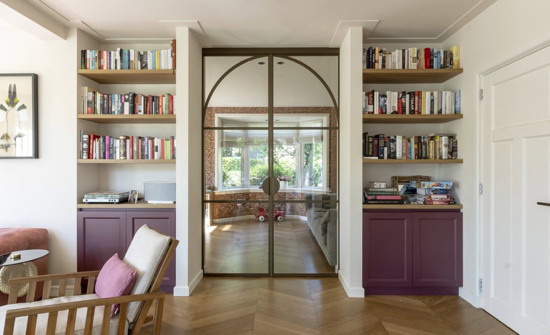 Glazen stalen door tussen woonkamer en speelhoek met boekenkasten, op maat gemaakte hoogwaardige stalen deuren en wanden van Aluwdoors.