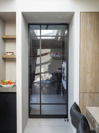 Glazen stalen scheidingsdeur met zwarte frame in moderne keuken.