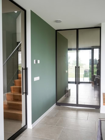 Strakke stalen deur met glazen panelen voor moderne binnen- of buitenruimte, afgewerkt in mat zwart met stijlvolle handgreep.