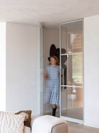 Rolgordijn stalen deur met glazen paneel, moderne interieurafwerking, op maat gemaakte stalen deur en wand, strakke en elegante scheidingswand.