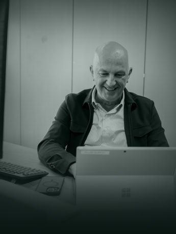 Modern man achter computer met stalen deur op kantoor.