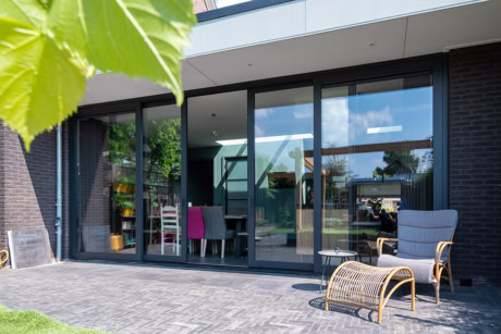 Strak moderne stalen schuifdeur met zwarte afwerking, perfect voor binnen en buiten, van Aluwdoors.