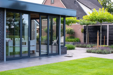 Elegante stalen schuifdeur met grote glaspartijen en op maat gemaakte zwart metalen frame voor modern tuinontwerp.