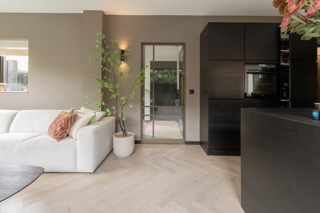 Modern stalen deur met glazen panelen in een strakke woonkamer.
