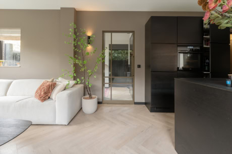 Modern stalen deur met glazen panelen in een strakke woonkamer.