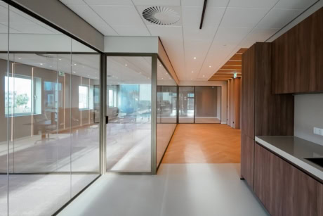 Moderne stalen scheidingswand en glazen deur in een kantooromgeving, op maat gemaakt voor duurzame en strakke indelingen.