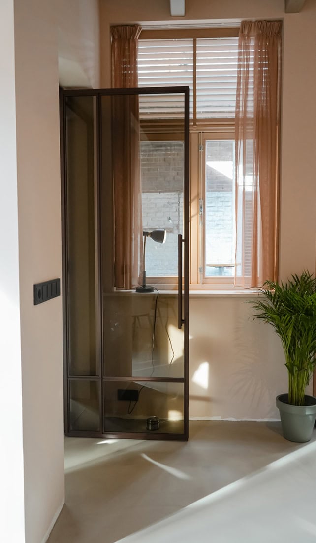 Geavanceerde stalen binnendeur met strakke zwarte lijst en glas in een modern interieur, perfect op maat gemaakt door Aluwdoors.