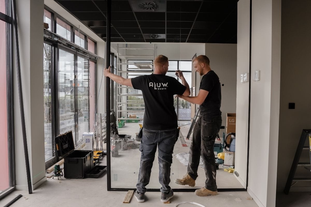 Moderne stalen deur en glazen wand installatie door professionals, maatwerk en hoogwaardige afwerking van Aluwdoors.