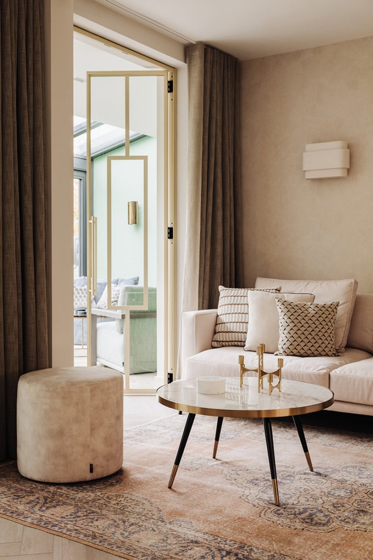 Moderne stalen dubbele scharnierdeuren met glazen panelen die toegang geven tot een lichte woonkamer.