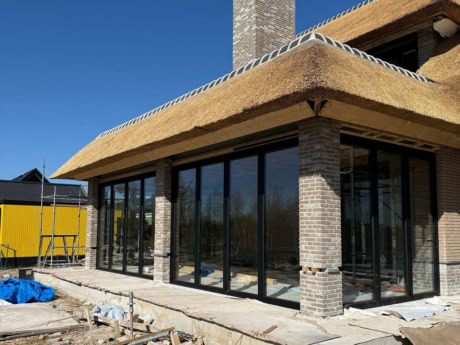 Moderne stalen schuifdeuren met grote glazen panelen voor een strakke en eigentijdse uitstraling, perfect voor het creëren van een open en lichte woonruimte.