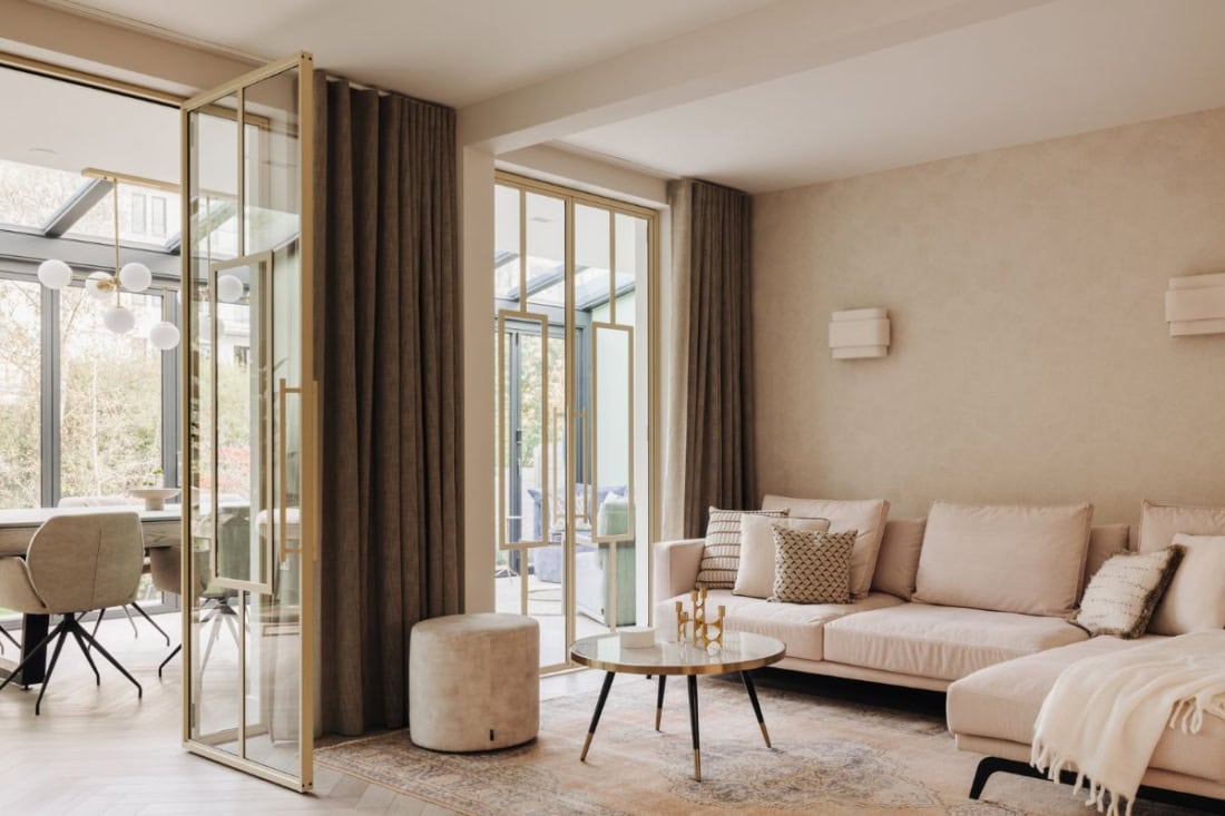 Moderne stalen schuifdeuren en wanden op maat in een lichte woonkamer voor stijlvolle afscheiding en veel natuurlijk licht.