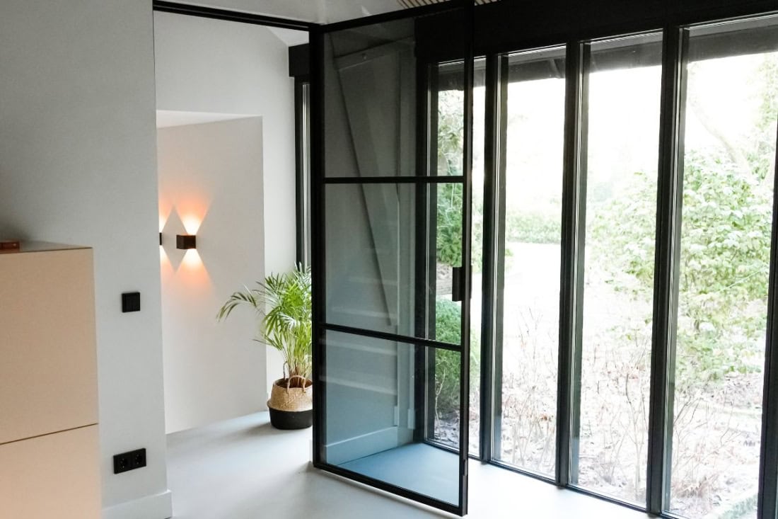 The hinged door including frame of Aluwdoors, containing the grey glass.