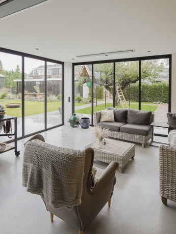 Sleek steel sliding doors in a modern living room overlooking the garden, custom-made by Aluwdoors.