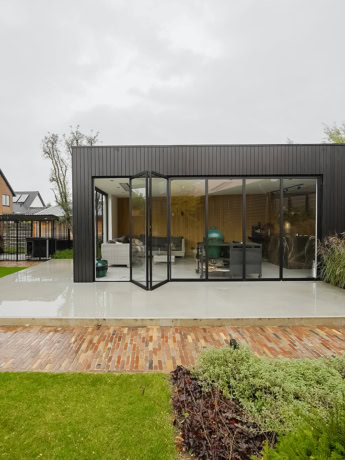 Modern steel sliding door in a bright living space with large window panels and black metal frame.