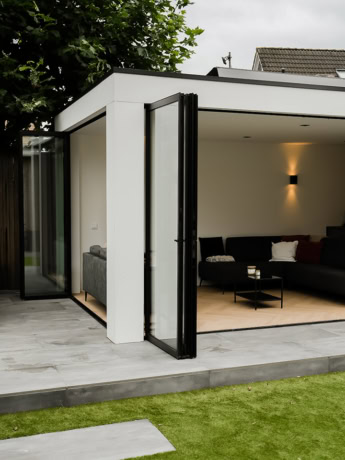 Elegant black steel folding doors that open seamlessly into a modern seating area for a spacious and bright interior.