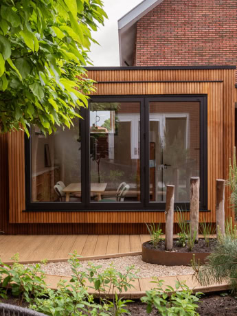 Moderne houten en glazen tuinkamer met grote ramen en strakke afwerking, perfect voor een stijlvolle buitenruimte of serre, ontworpen door Aluwdoors.