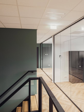 Aluwdoors bespoke steel interior doors and walls in modern office interior with glass partitions and wooden floor.