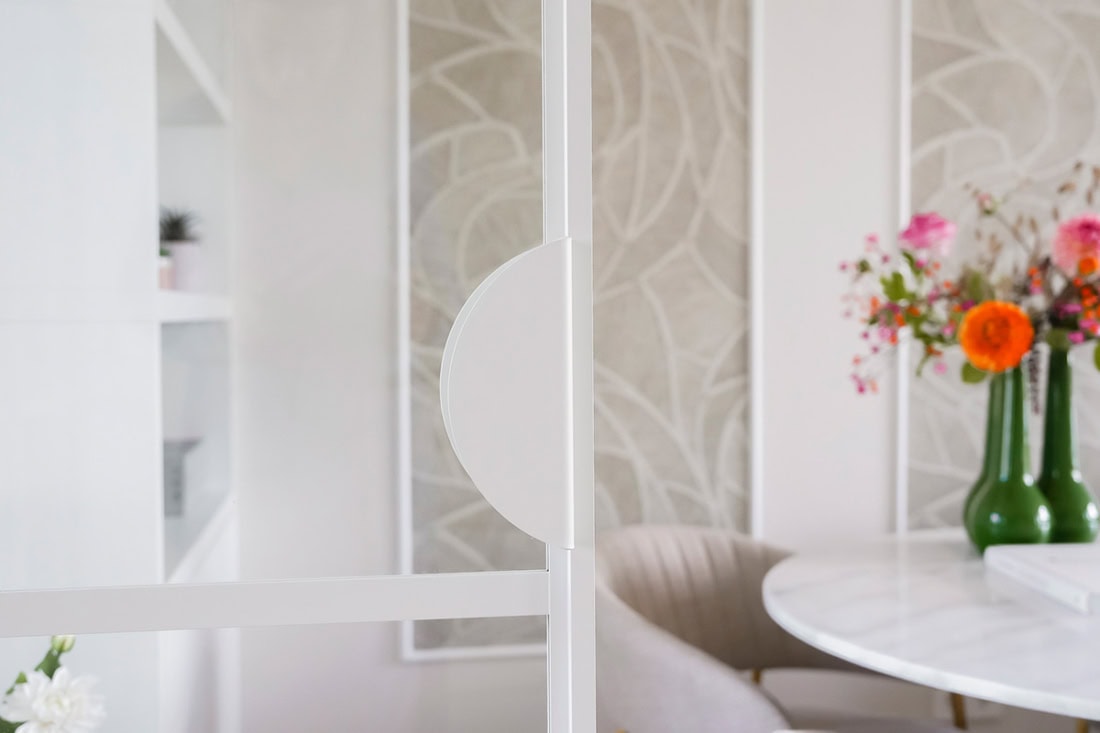 Strakke witte stalen deur met uniek halfmaan handvat in modern interieur.