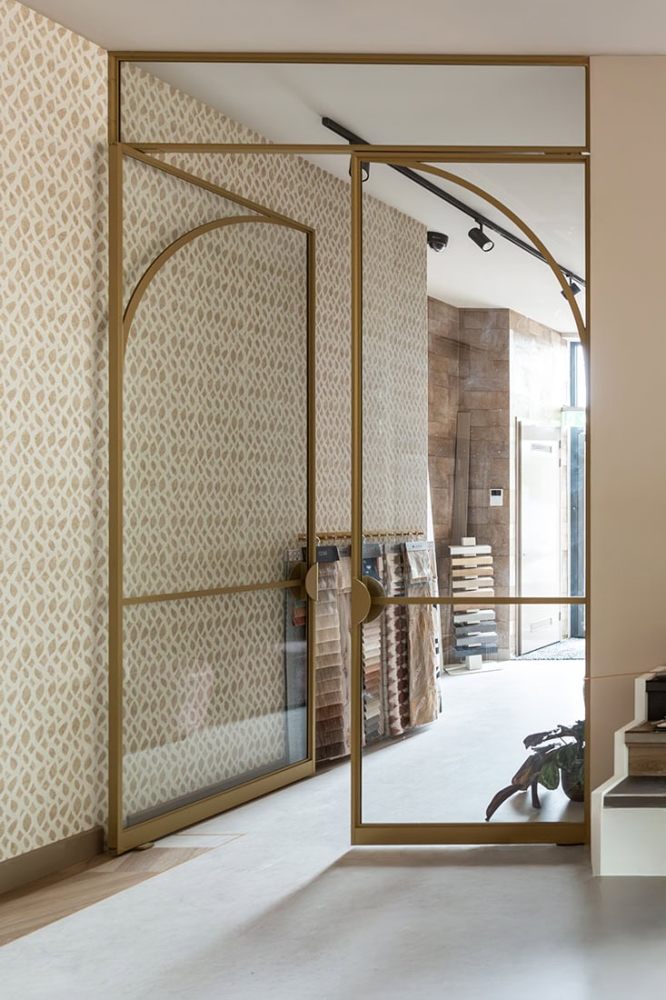 Strakke stalen scheidingswand met glas en goudkleurige afwerking voor een modern interieur.