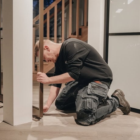 Hij bevestigt een stalen deur of wand, op maat gemaakt en van hoge kwaliteit, binnen een modern interieur.