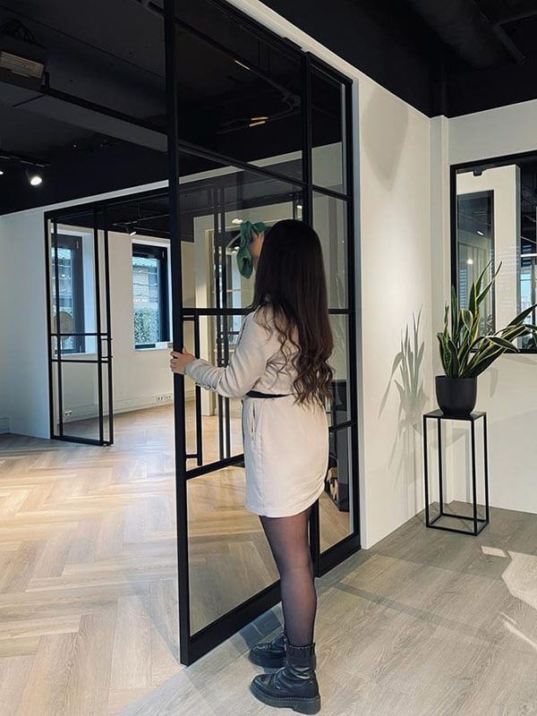 Stalen deur met zwart frame en glaspanelen in modern interieur, ideaal voor op maat gemaakte scheidingswanden en deuren, van Aluwdoors.