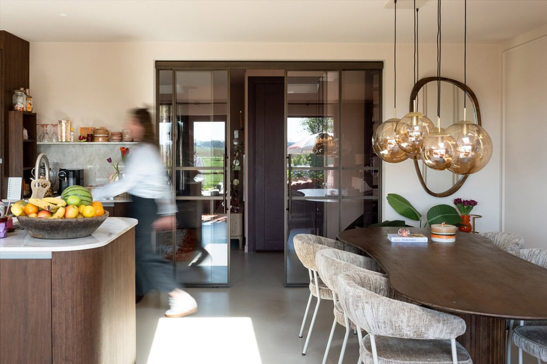 Hoogwaardige stalen schuifdeuren en wanden op maat in een modern interieur, gecombineerd met natuurlijke materialen en sfeervolle verlichting.