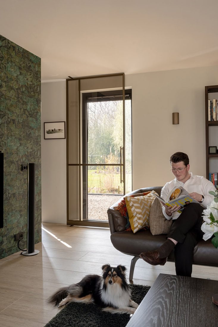 Geleidende stalen deur met schuifmechanisme, modern interieur met natuurlijke lichtinval en stijlvolle inrichting, huis met maatwerk stalen deuren en wanden.