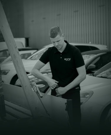 Herenmonteur installeert stalen deuren op maat bij parking met meerdere auto's, hoogwaardige afwerking, vakmanschap en maatwerk voor binnen- en buitendeuren, Aluwdoors.