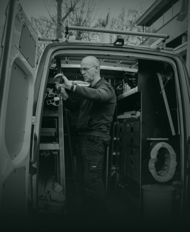 Huisbewaker voert reparaties uit in bedrijfswagen met gereedschap en apparatuur.