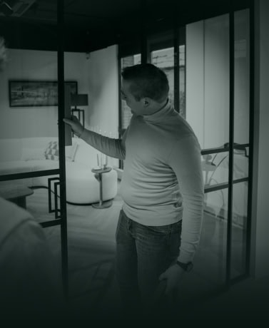 Stalen deur met zwart frame en glazen panelen in modern interieur, door een man geïnspecteerd voor maatwerk en kwaliteit, perfect voor stijlvolle binnen- of buitendeuren.