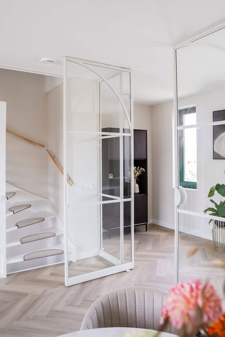 Glazen stalen deur met minimalistisch ontwerp en witte frame in moderne woonkamer.