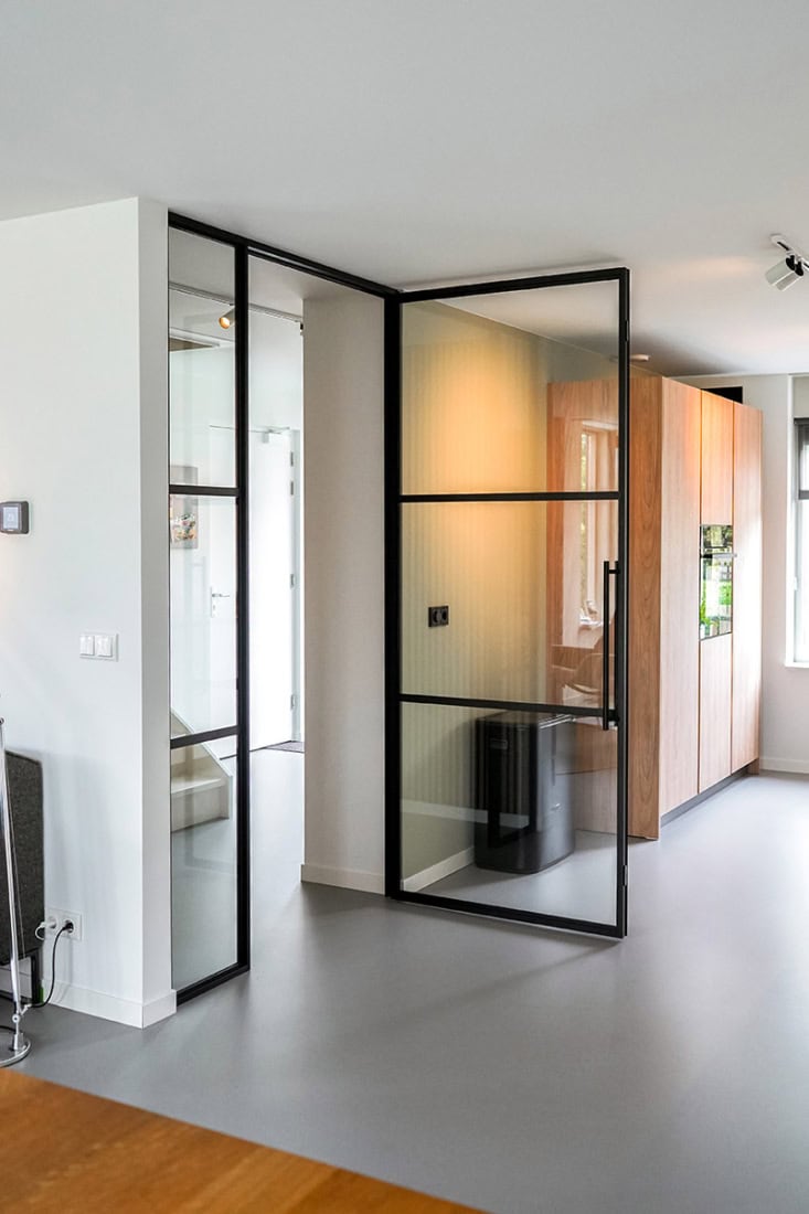 Elegante stalen tuinwand met zwart frame en glazen panelen, perfect voor moderne interieurs en buitenruimtes.