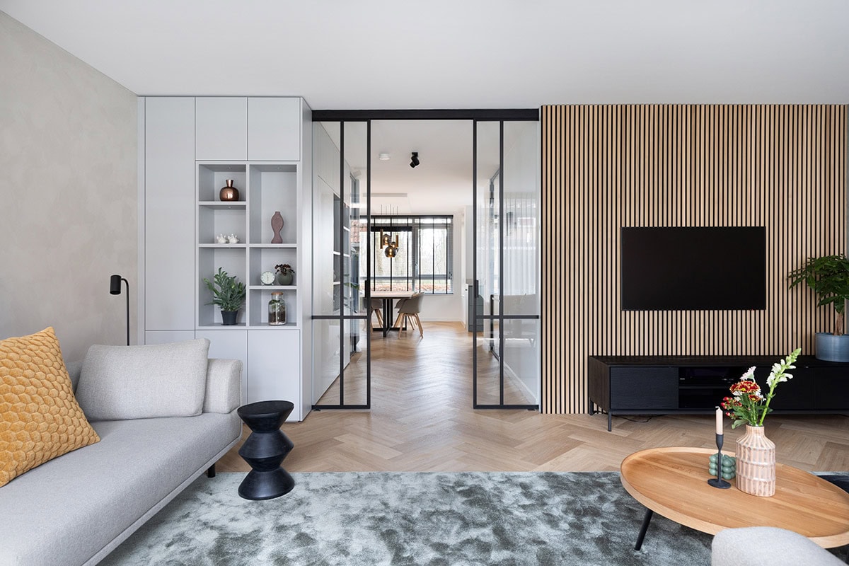 Strakke stalen schuifdeur met glas tussen woonkamer en eetkamer, modern interieur, op maat gemaakte industriële scheidingswand.