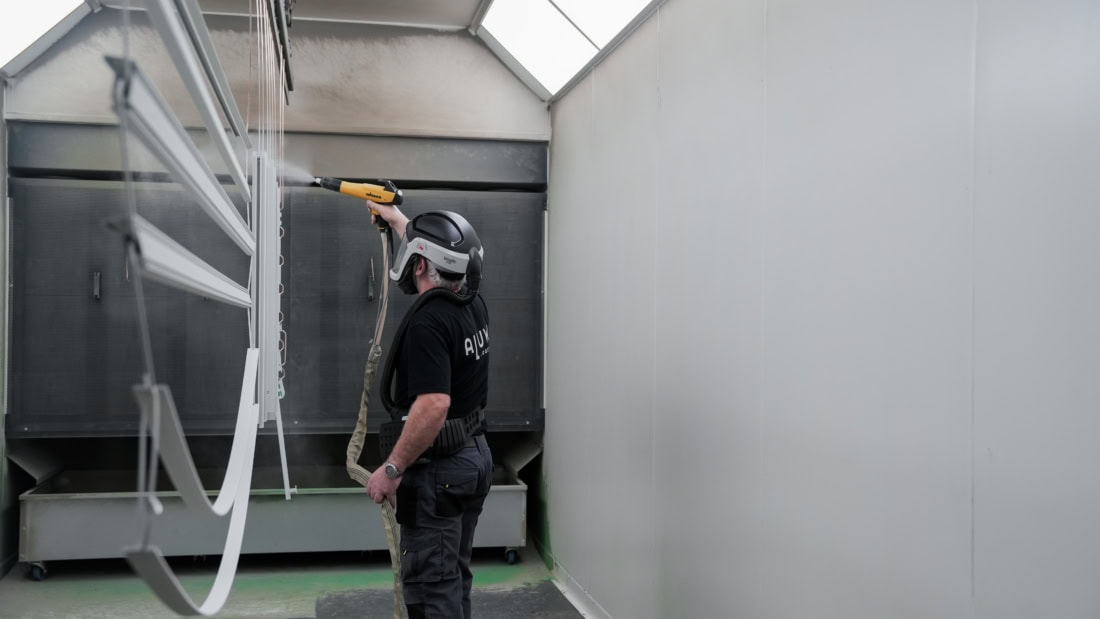 A man cleaning a steel door with a high-pressure cleaner in a high, bright room.